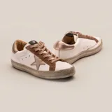 Zapatillas de cuero vacuno color blanco con aplique de estrella y talón superior color niquel italiano. Cartera en gamuza color taupe y suela de caucho.