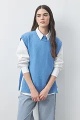 Chaleco tejido de punto con silueta relajada y diseño sin mangas. Presenta lazos laterales ajustables y cuello redondo.