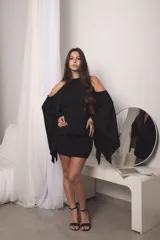 Vestido corto negro de manga murciélago, con aberturas en los hombros, espalda descubierta y diseño ajustado en la parte inferior.
