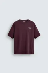 Camiseta de corte relajado color bordó, con cuello redondo y manga corta. Presenta un pequeño texto bordado en contraste en el pecho.
