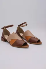 Sandalias de cuero color marrón, con combinaciones de color beige y naranja. Tiene tira ajustable con hebilla en el tobillo y taco bajo.