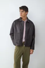 Campera de efecto cuero en color marrón oscuro, con cuello camisero, cierre frontal con cremallera y bolsillos frontales tipo parche.