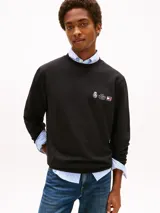 Buzo de cuello redondo Tommy Hilfiger, color negro, con logo bordado y detalle de escudo en el pecho. Presenta puños y ruedo acanalados.
