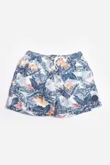 Short de baño celeste con estampado de hojas pequeñas en tonos verdes y blancos. Cuenta con cintura elástica con cordón ajustable, bolsillos laterales y un parche circular con logo en la parte inferior.