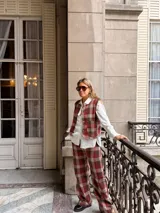 Pantalón de corte recto con estampado de cuadros en tonos rojos, marrones y beige. Presenta un diseño de tiro medio y pernera amplia.