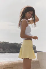 Shorts de tiro medio confeccionados en tejido satinado color amarillo con estampado de lunares blancos y bajo con vuelo.