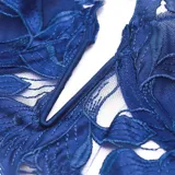 Conjunto de lencería azul con bordados florales transparentes, compuesto por un soutiene bralette de escote pronunciado y una bombacha cavada con tiras finas.