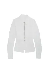 Camisa de manga larga en tejido popelín color blanco, con cuello clásico, cierre frontal de cremallera metálica y bolsillos frontales tipo parche. Presenta un diseño entallado con abertura en el bajo.