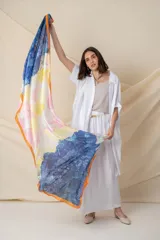 Pañuelo cuadrado de seda con estampado abstracto en degrade de colores azul, amarillo, blanco y rosa, con borde naranja.