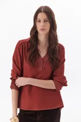 Blusa blanca de manga larga con escote en V y cuello camisero.