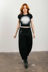 Pantalón negro de corte ancho con bolsillos laterales y cadena metálica decorativa.