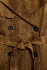 Trench corto de efecto ante color marrón, con cuello solapa, cierre cruzado con botones y cinturón ajustable del mismo tejido. Presenta mangas largas con trabillas en los puños y bolsillos delanteros de vivo.