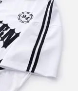 Remera de manga corta en tejido sintético color blanco, con cuello redondo y diseño de estilo deportivo. Presenta estampado frontal con lettering gótico y detalles laterales en tejido microperforado.