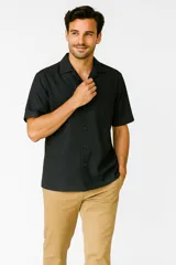 Camisa de algodón color negro, con cuello tipo cubano, manga corta y bolsillo frontal.