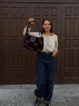 Cartera de hombro confeccionada en cuero y gamuza con diseño de damero, combinando paneles de texturas lisas y aterciopeladas. Presenta una manija trenzada y detalles de costuras artesanales en los laterales.