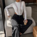 Body de manga larga confeccionado en tela semitransparente color blanco, con diseño de paneles estructurados y cuello alto.
