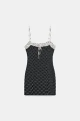Vestido corto entallado con estampado de lunares, tirantes finos ajustables y escote redondo con detalle de frunces y lazada frontal. Presenta un diseño combinado con contraste de colores en la parte superior y cierre de cremallera oculta en la espalda.