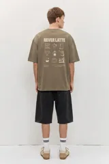 Remera de corte oversize color blanco tiza, de manga corta y cuello redondo, con pequeño estampado gráfico azul en el pecho.