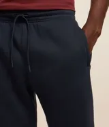 Pantalón deportivo de corte jogger, color negro, con cintura elástica ajustable mediante cordón, bolsillos laterales y puños acanalados en los tobillos. Confeccionado en tejido de algodón con interior felpudo.