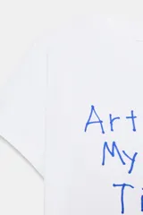 Camiseta blanca de manga corta y cuello redondo con estampado frontal en azul que dice "Artist In My Free Time".