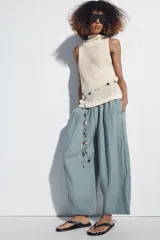 Pantalón barrel negro confeccionado en 100% lino, con tiro medio y cintura elástica fruncida. Cuenta con bolsillos laterales y falsos bolsillos de vivo en la espalda, de corte amplio y holgado.