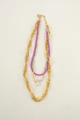 Collar de tres vueltas con cadena dorada gruesa, cadena de cuentas de colores y cadena de cuentas lilas con dije de perla.