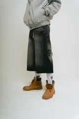 Bermuda de jean estilo carpintero, corte baggy, color negro lavado con efecto degradado. Presenta bordados en la parte trasera con tipografía gótica que dice "Lucca Bossio". Incluye bolsillos grandes y bolsillo lateral de carpintero.