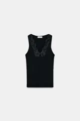 Camiseta negra de corte ajustado (slim fit) con escote pico y manga sisa. Presenta una aplicación de encaje a tono en el escote.