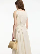 Vestido midi de algodón color crudo, con diseño tipo túnica, cuello redondo y lazo ajustable en la cintura para entallar la silueta. Presenta detalles de bordado sutil en el cuello y las sisas.