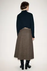 Falda de tiro alto con diseño evasé, confeccionada en tejido con lana. Presenta un patrón de cuadros, un pliegue frontal y un bolsillo con botón en la parte delantera. Cierre mediante cremallera oculta.