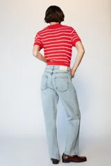 Jeans de tiro alto con diseño de cintura cruzada, cinco bolsillos y pernera recta con bajo sin costura. Cierre frontal con cremallera y botones.