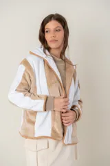 Campera de peluche con diseño de paneles verticales en colores blanco y beige. Presenta capucha, cierre frontal y puños de tejido elástico en tono contrastante.
