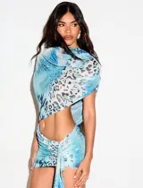 Set de dos piezas confeccionado en tejido semitransparente con estampado animal print en tonos celestes, compuesto por un top tipo pañuelo asimétrico y una minifalda con frunces y lazo lateral ajustable.