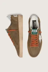 Zapatillas Golden Goose modelo Ball Star, confeccionadas en gamuza encerada marrón con efecto vintage. Tienen estrella lateral blanca, cordones naranjas, contrafuerte plateado en el talón y suela de goma con acabado envejecido.