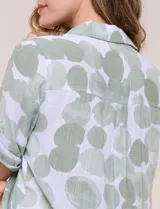 Camisa de lino sintético con estampado floral en tonos azules y beige sobre fondo blanco, de corte holgado, mangas tres cuartos y cuello camisero.