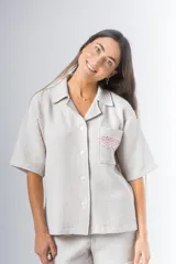 Conjunto de pijama de tela waffle color crema, compuesto por una camisa de manga corta con botones, bolsillo y detalle de broderie, y un short con elástico y cordón en la cintura con terminación de broderie.