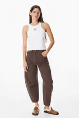 Jean de corte balloon en color azul marino, con cintura alta, cierre frontal con botón y bolsillos laterales. Presenta costuras laterales curvadas que definen su silueta amplia y relajada.