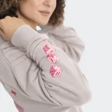 Buzo con capucha color gris topo, de corte holgado, con bolsillo frontal tipo canguro y logo de la marca bordado en color rojo en el pecho.