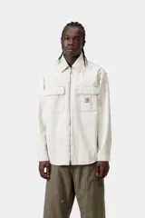 Sobrecamisa Carhartt WIP modelo Mercer Shirt Jac, color gris con diseño a rayas finas verticales. Cuenta con cierre frontal de cremallera, bolsillos frontales con solapa y botón, y parche con el logo de la marca en el pecho.