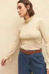 Polera color beige de algodón, con cuello alto y mangas largas acampanadas.