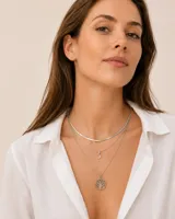 Collar triple de acero plateado compuesto por una cadena estilo cola de ratón en la capa superior, una cadena fina intermedia con un dije en forma de media luna, y una cadena larga inferior con un dije circular colgante del Árbol de la Vida.