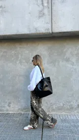 Cartera tipo shopper de cuero negro con acabado brillante, diseño amplio, doble asa de hombro y cierre superior.