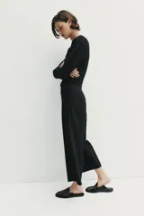 Pantalón culotte negro de tiro alto con bolsillos delanteros, pernera ancha y corta, y raya marcada al frente. Cuenta con cierre lateral con cremallera oculta.