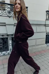 Cazadora bomber de Zara, de color bordó, con cuello de solapa, manga larga, bolsillos de vivo en el delantero y bajo elástico. Cuenta con cierre frontal de cremallera metálica.