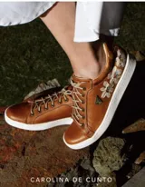 Sneakers de cuero terracota con detalles de flores pintadas a mano, cordones claros y suela blanca.