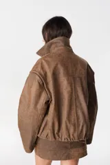 Campera de cuero marrón con mangas desmontables, permitiendo su uso como chaleco. Presenta cuello camisero, cierre frontal y diseño versátil.