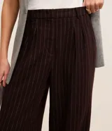 Pantalón de vestir de polivelour marrón con finas rayas verticales blancas, de corte recto y cintura alta, con cierre tradicional, pliegues y bolsillos.