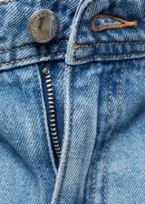 Pantalón de jean estilo denim con corte de pierna ancha y cintura alta. Presenta dos bolsillos de parche en la parte delantera, dos bolsillos traseros, trabillas para cinturón y cierre frontal con botón y cremallera.