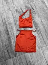 Top negro asimétrico con un solo tirante ancho y un corte en el pecho.