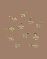 Capa de paño color rojo con corte amplio y caída natural. Presenta detalles de dijes metálicos en baño de oro distribuidos en la espalda y una etiqueta de cuero con el logo de la marca en la parte superior.